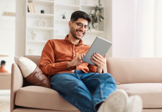 Happy man sitting on sofa | Flooring and More